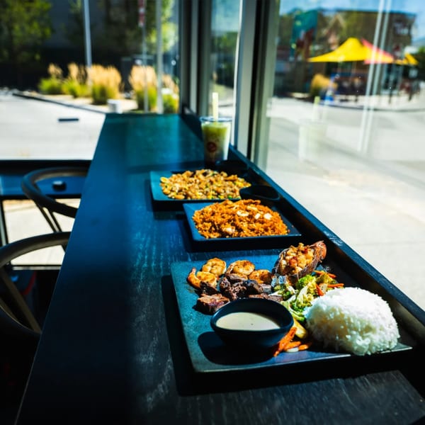 Fried rice, seafood rice, and a surf and turf platter lined up on a window counter