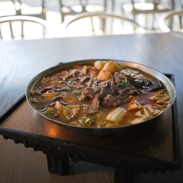 Hot pot with beef on a stand with white chairs behind