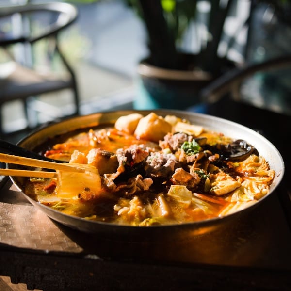Spicy hot pot with beef and tofu, chopsticks lifting cabbage