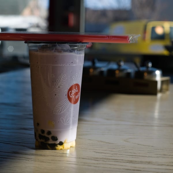 Taro boba drink with red straw on a sunlit table