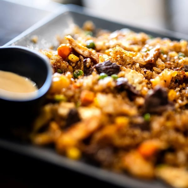 Close-up of fried rice with beef and vegetables and a dipping sauce