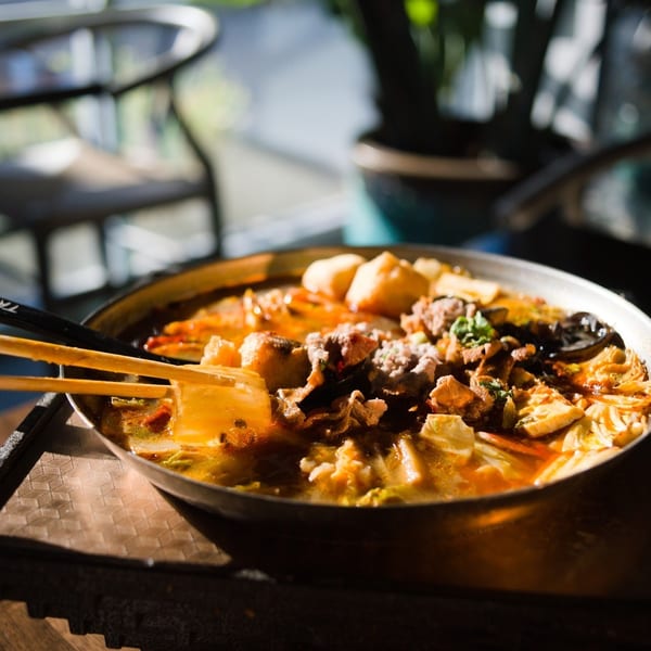 Spicy hot pot with pork and tofu, chopsticks resting on the bowl