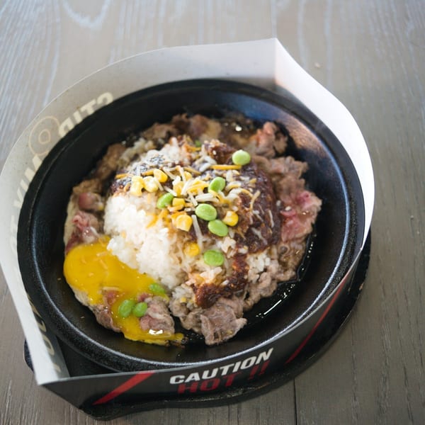 Sizzling stone bowl with steak, rice, corn and edamame
