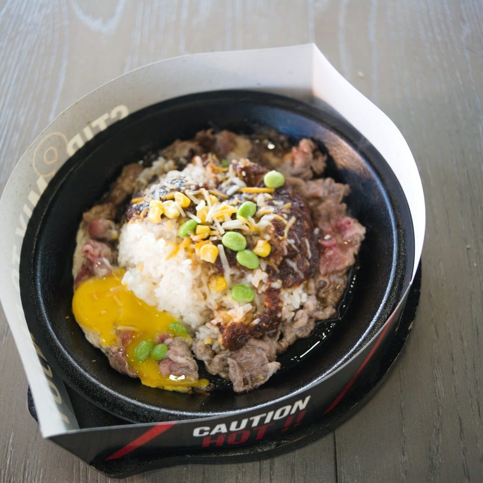 Sizzling stone bowl with steak, rice, corn and edamame